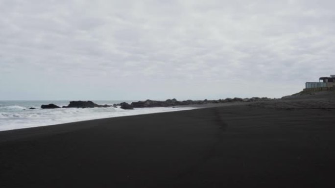 在阴天，pichilemu海滩的黑沙全景。