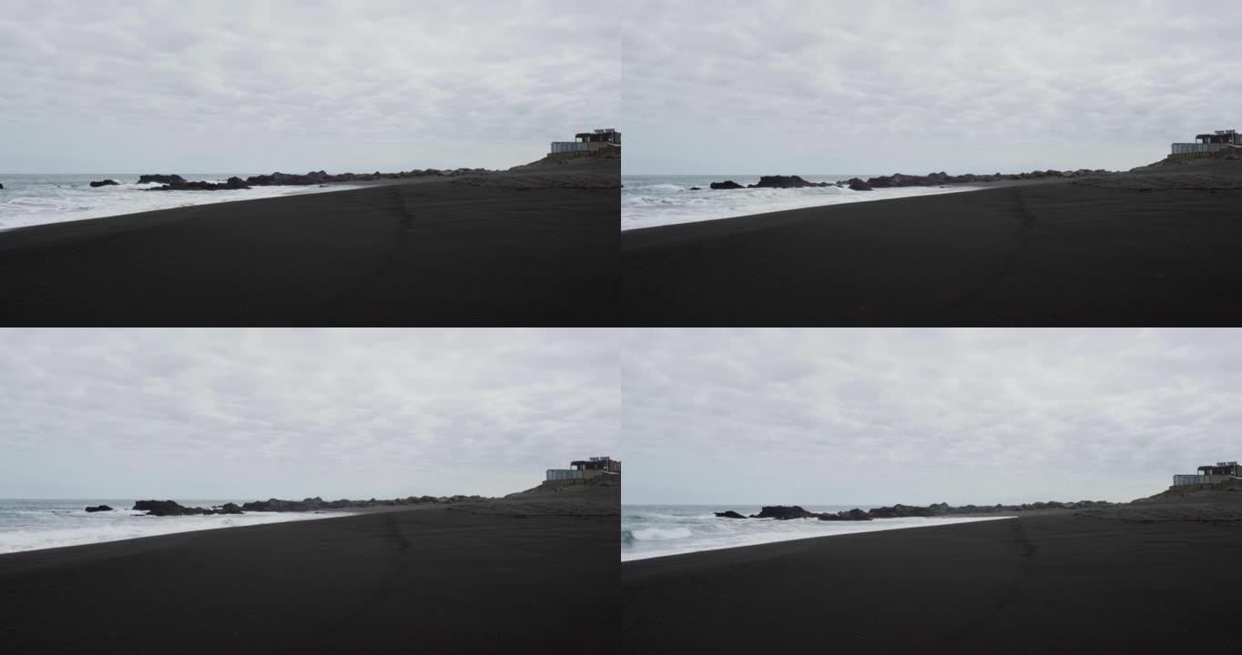 在阴天，pichilemu海滩的黑沙全景。