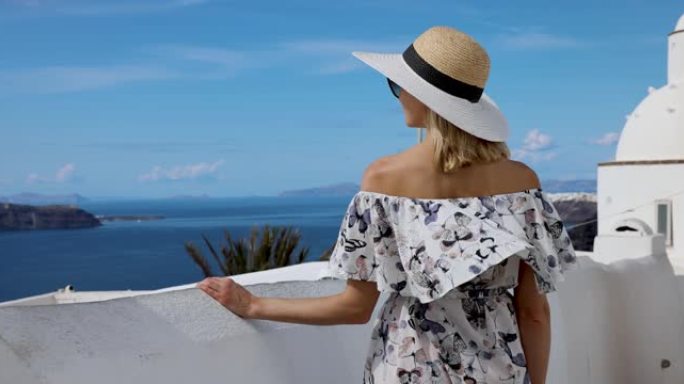 在圣托里尼岛，戴着草帽，穿着海景的女人。希腊