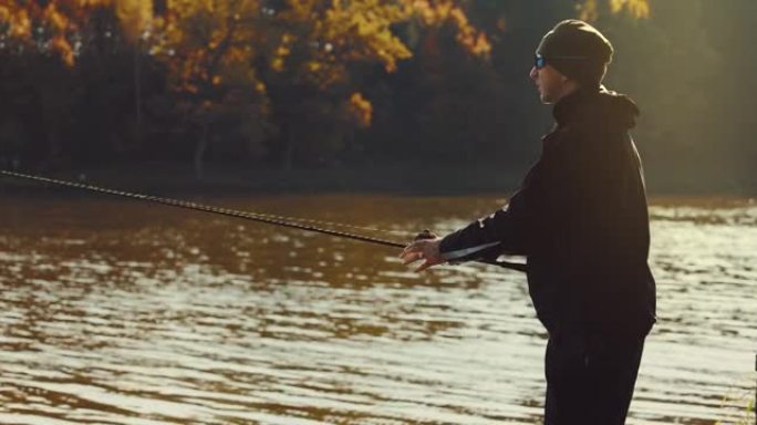 在阳光明媚的秋日，渔夫将纺纱杆投入湖中。引诱钓鱼