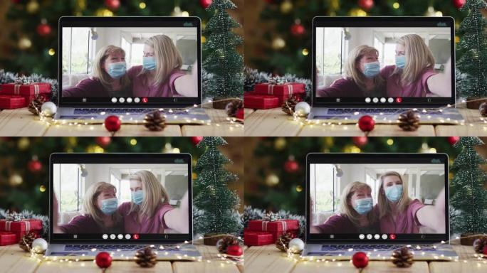 母亲和女儿戴着笔记本电脑上的视频面罩，带有圣诞节装饰和树木