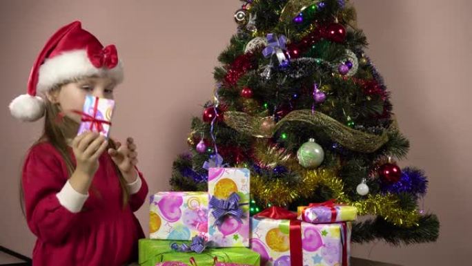 一个打扮成圣诞老人的小女孩解开了礼品盒和清单上的丝带。4k
