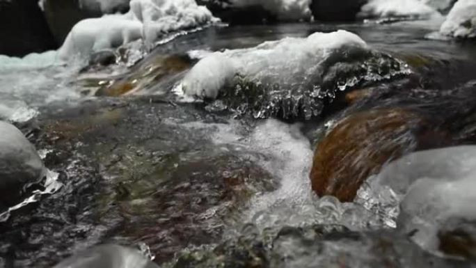 在针叶林中流淌的山区河流的死水特写。冰雪中的冰冻石头。横向移动滑动。广角