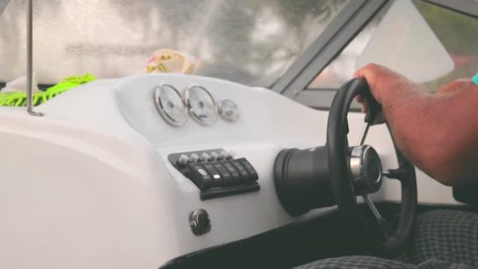 一个驾驶快艇掌舵的老人的手。船舵和人的手