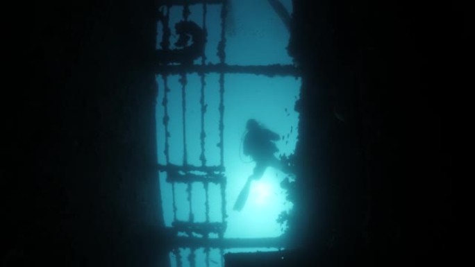 独特的视野，仰望一名潜水员越过沉没的沉船的轮廓。