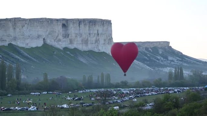 彩色热空气心形气球在日落时以慢动作在蓝天上飞行，情人节快乐概念。4k HDR高质量镜头