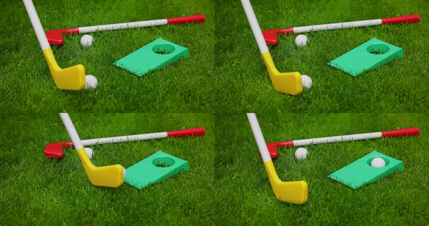 玩具高尔夫-用塑料高尔夫球杆将球击入洞中。花园游戏