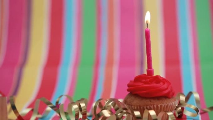 雪佛龙图案设计在彩色条纹背景的纸杯蛋糕上燃烧的蜡烛上
