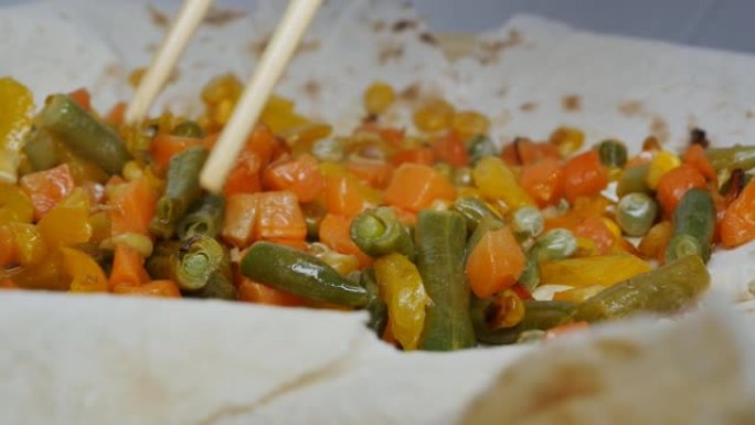 竹签将油炸的混合蔬菜放在皮塔饼面包中。食物摄入