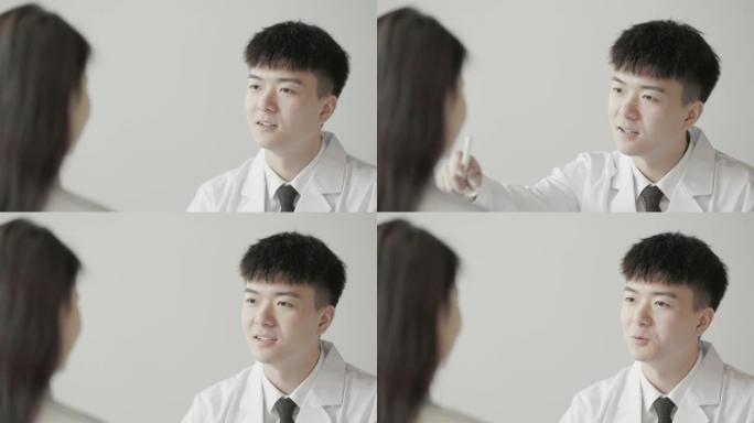 年轻的亚洲男医生正在与坐在他对面的女患者讨论他们的病情。美容医生和整形外科医生在亚洲很受欢迎