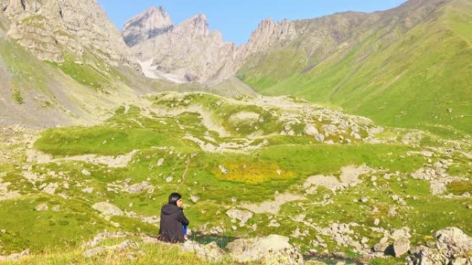 静态观点体贴的女人坐在岩石悬崖上，独自欣赏风景如山的全景。