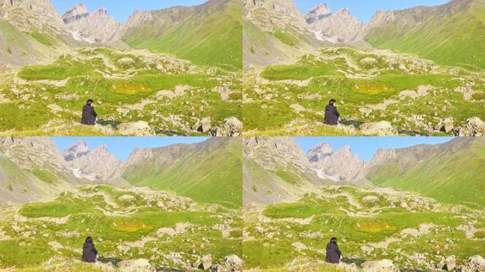 静态观点体贴的女人坐在岩石悬崖上，独自欣赏风景如山的全景。