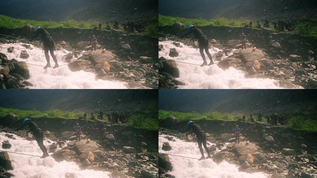一名游客在绳索形式的垂直绳索的帮助下过河，用登山扣固定。