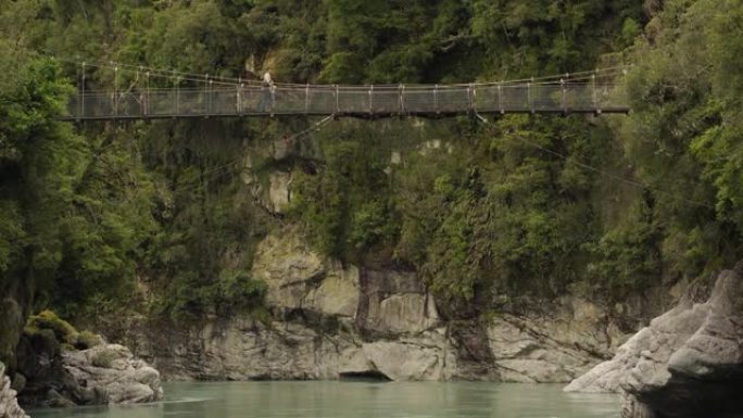 霍基蒂卡峡谷吊桥和一个穿过它的人。新西兰西海岸。