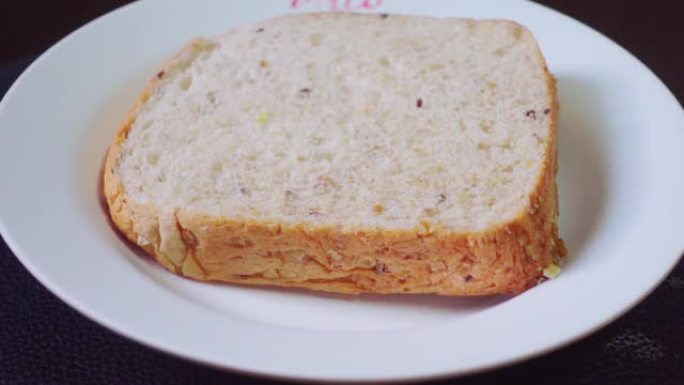 将面包放在白色的盘子上，上面放有加糖的炼乳作为早餐