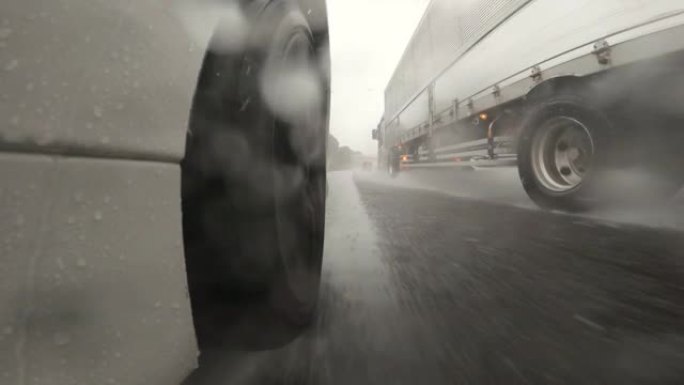 在大雨中，在高速公路上的半卡车旁边行驶。