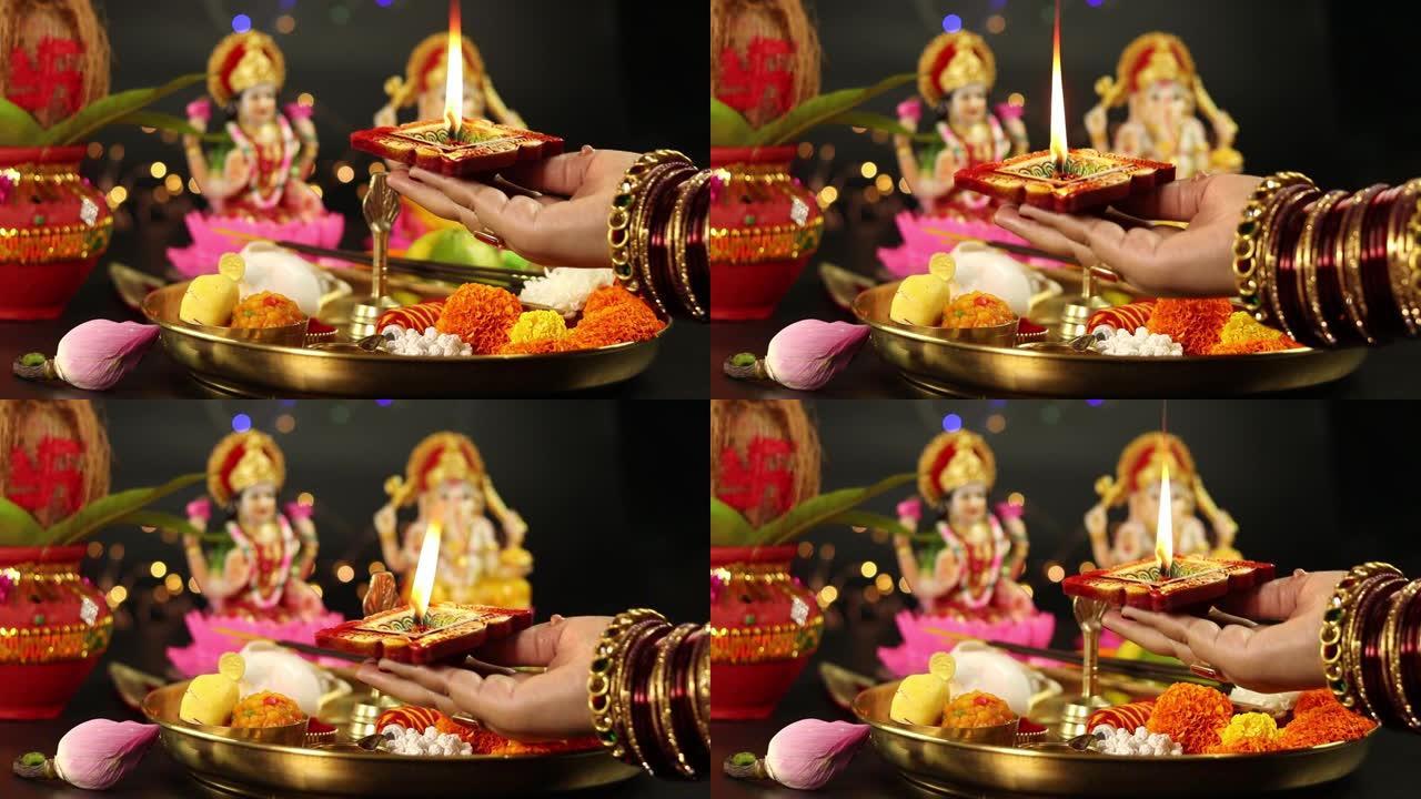 手镯上的女孩的手拿着粘土迪亚深直径灯，上面用Pooja Thali、鲜花、米泰、阿加巴蒂和做Aart