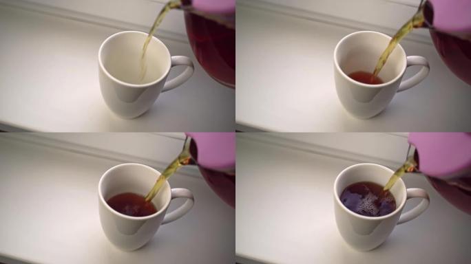 人类将玻璃茶壶中的香茶倒入白色陶瓷杯中。