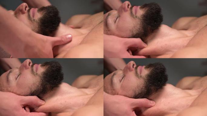 特写男性按摩治疗师让客户运动员在黑暗舒适的水疗按摩沙龙做颈部按摩。专业运动按摩