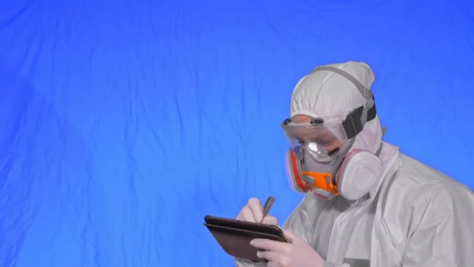 呼吸器的科学家病毒学家用手写笔在平板电脑中书写。戴着防护医用口罩的男子。色度键蓝色。