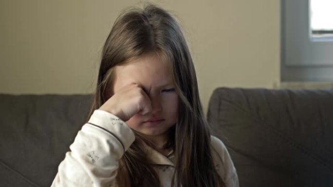 一个刚醒来的6-7岁女孩擦了擦眼睛