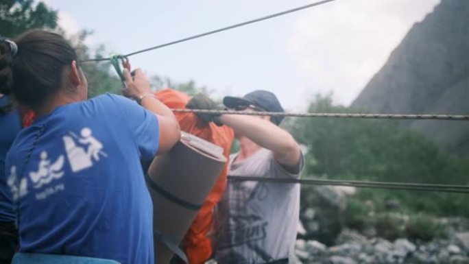 游客穿越一条快速的山河时，将背包放在卡宾枪上。