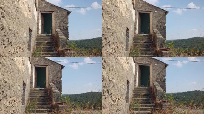 意大利省山区的废弃乡村住宅，破旧的房屋，楼梯上长满了绿色植物，门窗破损，外墙灰泥被毁。战后时期的空h