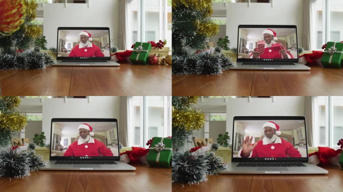 微笑的非洲裔美国男子穿着圣诞老人服装在笔记本电脑上的圣诞节视频通话