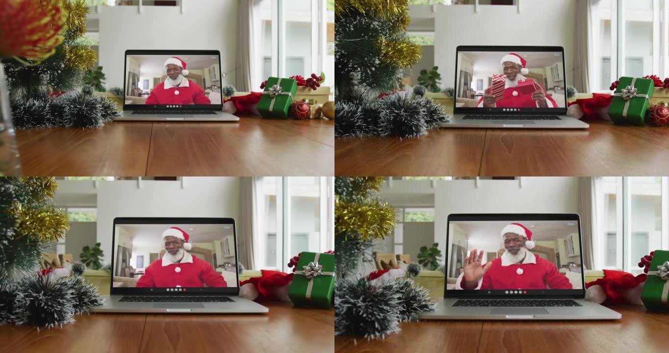 微笑的非洲裔美国男子穿着圣诞老人服装在笔记本电脑上的圣诞节视频通话