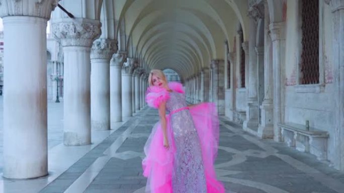 威尼斯隧道中穿着粉红色优雅连衣裙的女孩