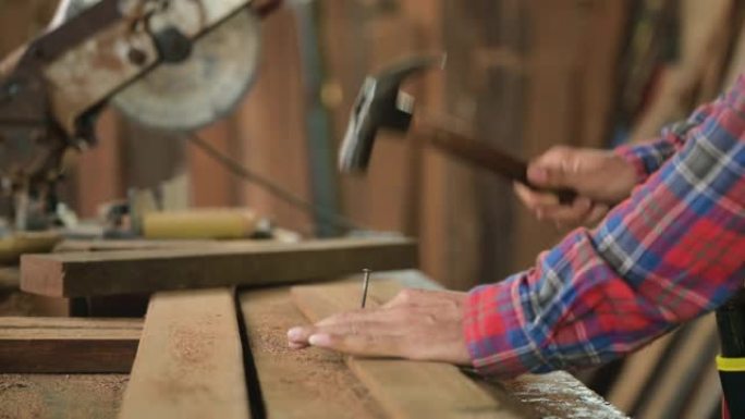木匠或木匠的特写镜头穿着格子衬衫站立工作钉锤成木板。