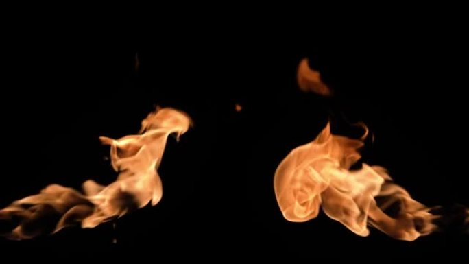 黑暗中，两场火焰从屏幕的不同侧面燃烧。真正的篝火、燃烧器或火炬在黑色背景下闪烁。高速喷火器随火焰爆炸