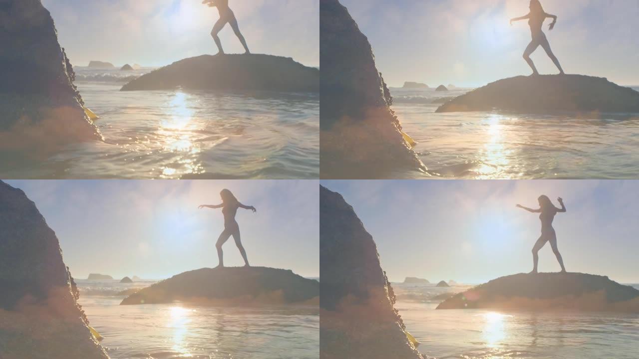 晴天站在海边的岩石上练习瑜伽的女人的剪影
