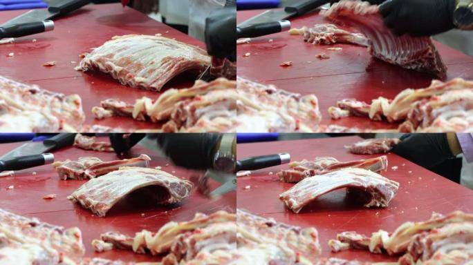 戴着黑手套的屠夫正在肉店切羊排肉。厨师用白色围裙切肉