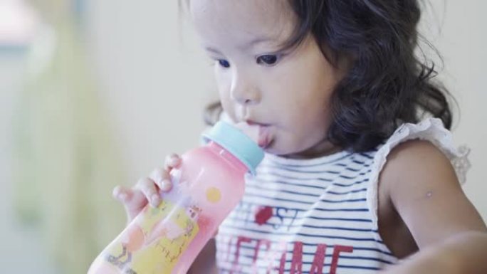 一个可爱的小女孩2岁在家喝奶瓶牛奶的特写肖像。儿童止渴健康食品概念