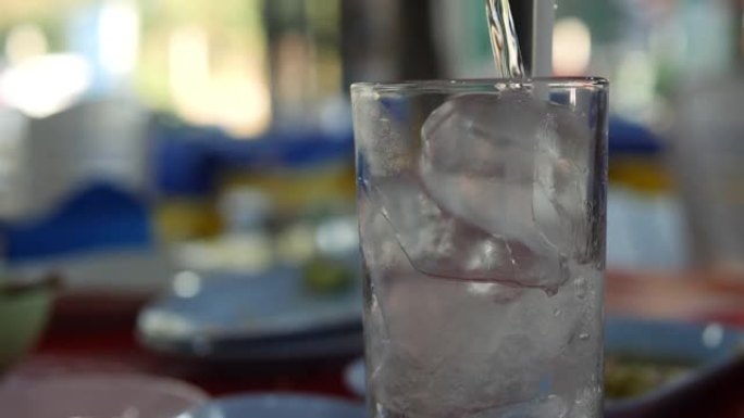 将水倒入装有冰的透明玻璃杯中。