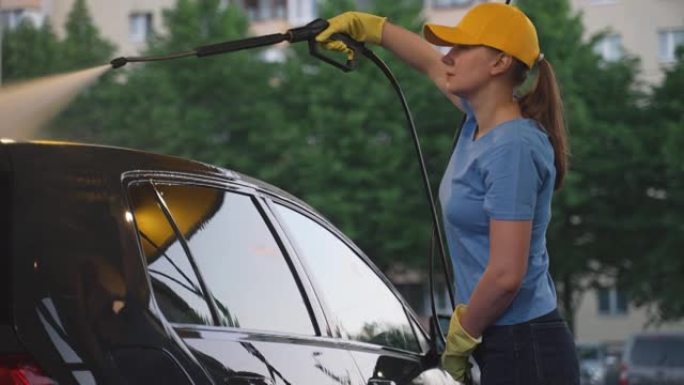 女人在统一的清洁车上使用高压水。洗车服务。