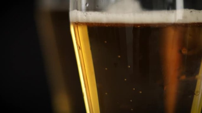 两杯冰冷的金色啤酒，黑色背景上有气泡。在聚会，假期，啤酒节或圣帕特里克节喝酒