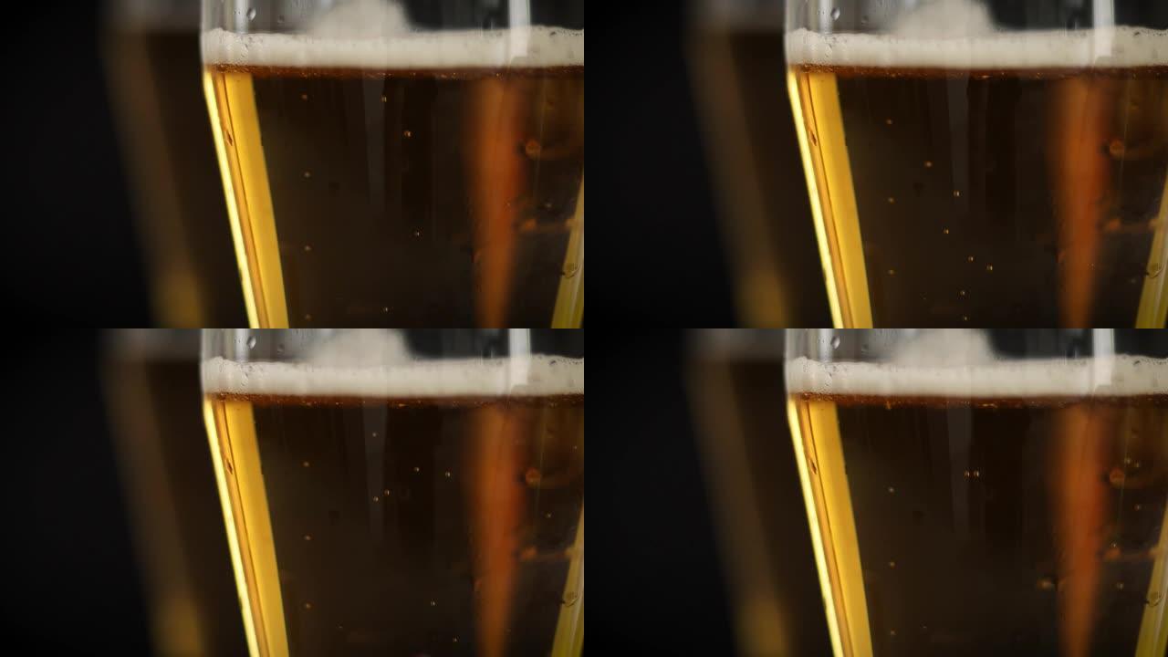 两杯冰冷的金色啤酒，黑色背景上有气泡。在聚会，假期，啤酒节或圣帕特里克节喝酒