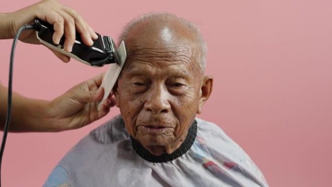 亚洲高级男子在家理发。