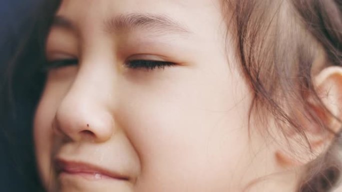 可爱的5岁亚洲女孩的脸特写4k在母亲的拥抱中哭泣，并通过她的眼睛表达人们的悲伤，不快乐，沮丧和悲伤的
