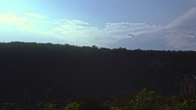 一名跳伞者带着机翼降落伞在空中盘旋的后视图。行动。专业的天空潜水员在灰色多云的天空背景上飞行时拉动吊