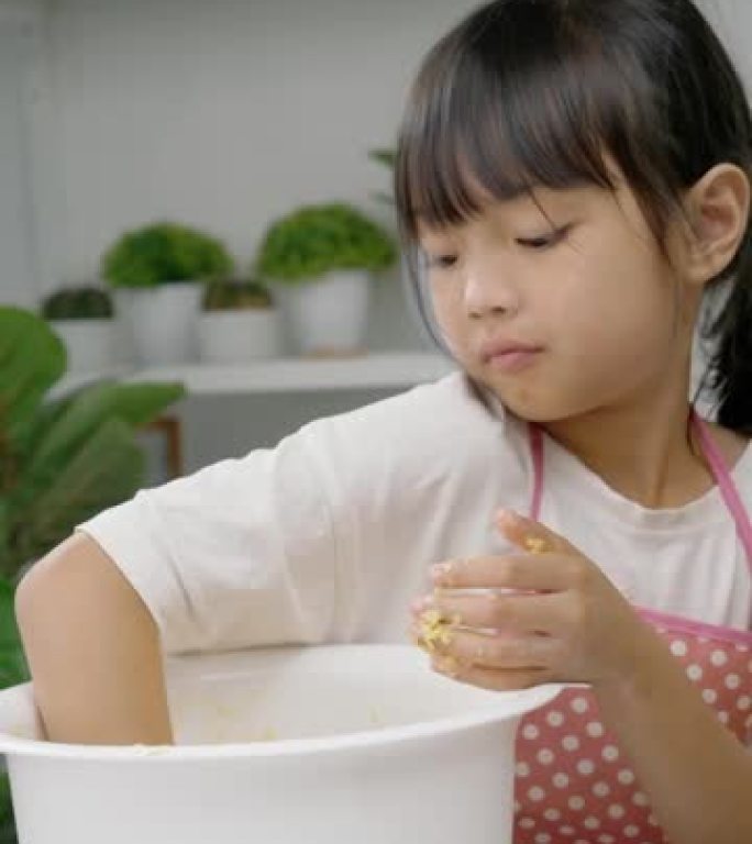 快乐的亚洲儿童在家学习制作饼干，女孩在搅拌碗中脱粒糕点面团。