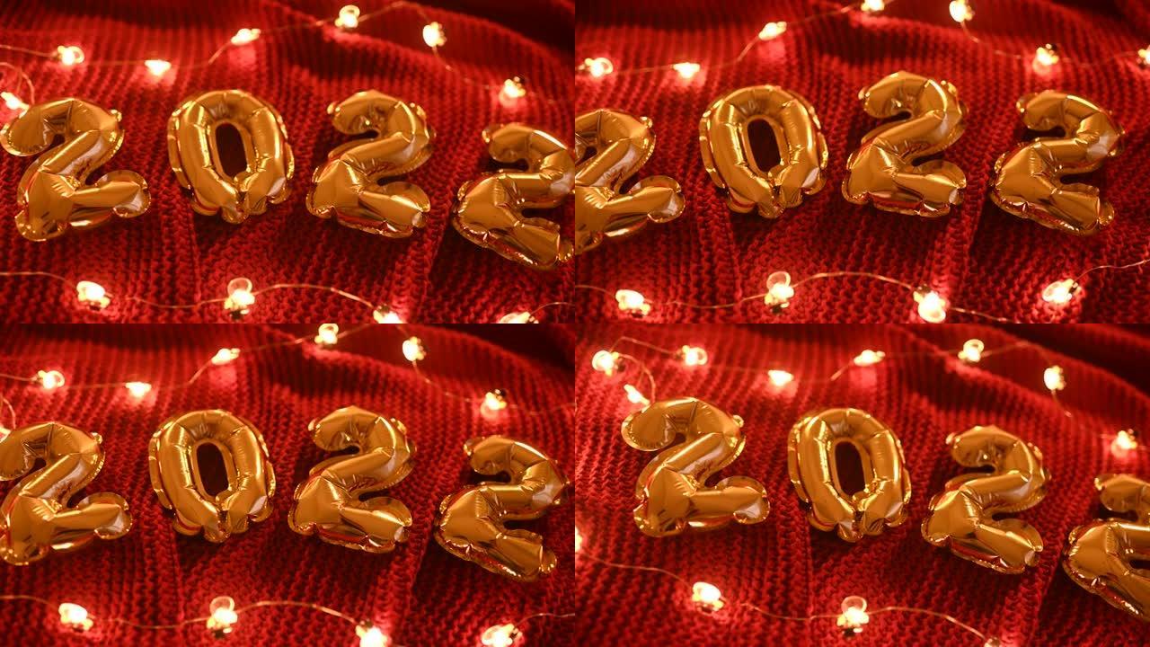 数字2022在一个红色针织舒适的格子和圣诞灯的背景