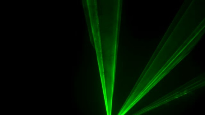 黑色工作室背景上的激光霓虹灯的动态绿色光束在烟雾中旋转和频闪。舞台全息图的展示。假日和派对的照明设备