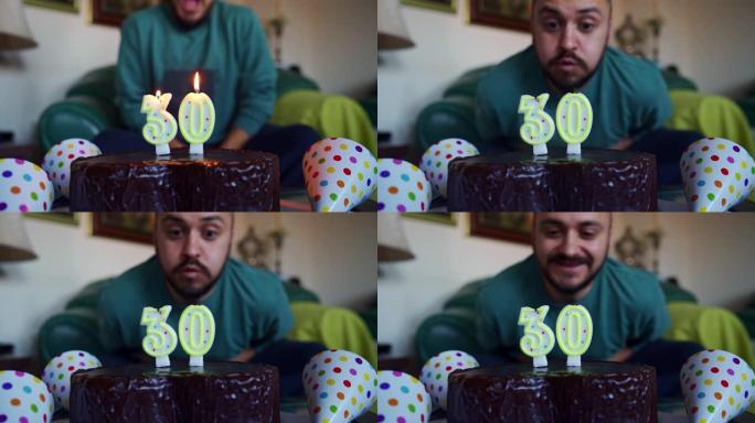 激动的年轻人在家里庆祝自己的30岁生日时，吹着生日蛋糕上的蜡烛
