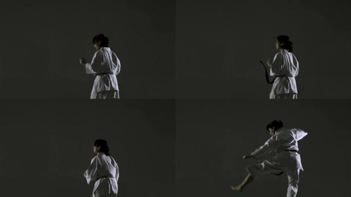 空手道女孩练习跳脚，穿着和服，在黑暗的背景上。以120fps记录的慢动作