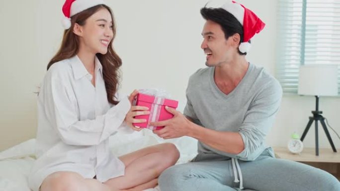 亚洲美女收到男友送的圣诞礼物礼盒。迷人的年轻女孩为丈夫的惊喜感到高兴和兴奋，并准备在家里一起庆祝节日