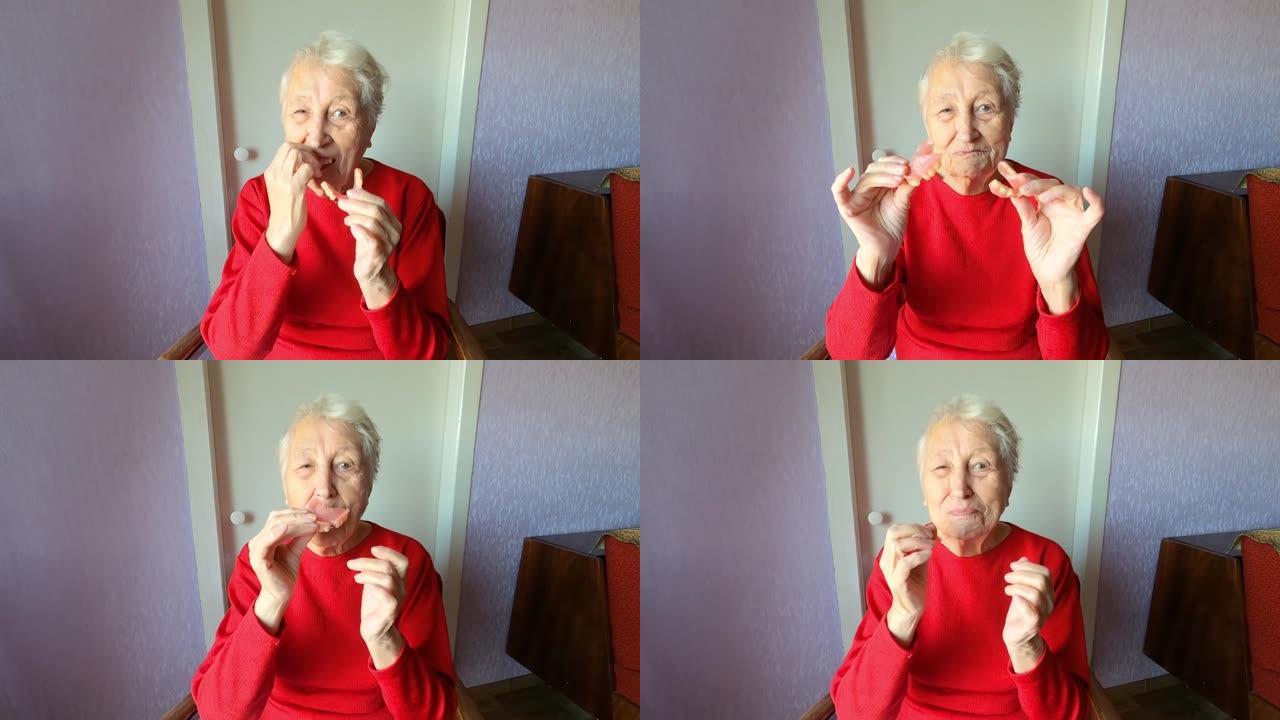 牙科概念。老年女性90岁插入义齿。高级女性白发使用假牙在灰色背景。老病人在工作室安装了人造下巴。柔性