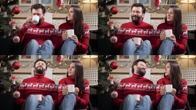 圣诞节，新年，前夜。幸福的夫妻男人和女人坐在地板上，看着圣诞树，喝茶和聊天。慢动作